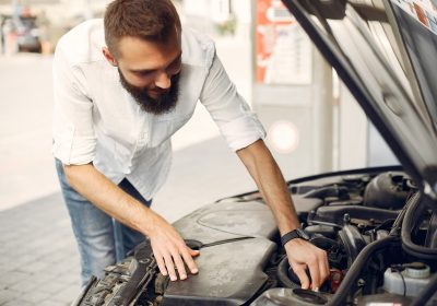 Man checks the engine. Guy checks his car Male in a white shirt.